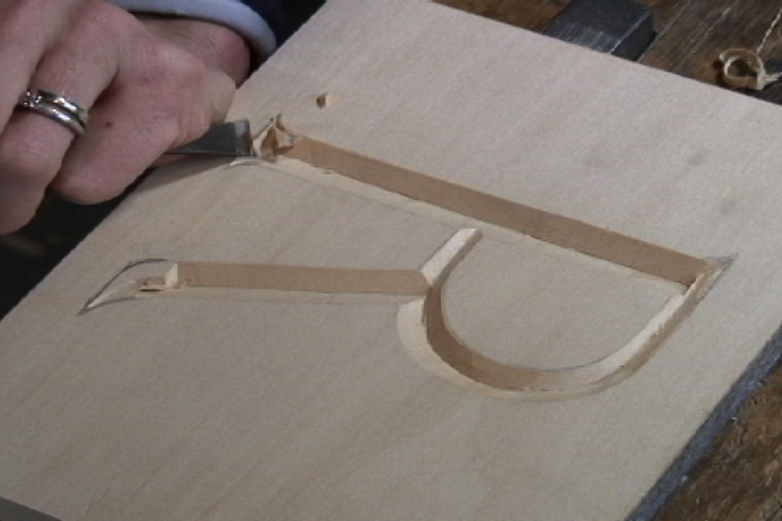 With a straight chisel make a 45 degree angle along the bottom edge of the letter.